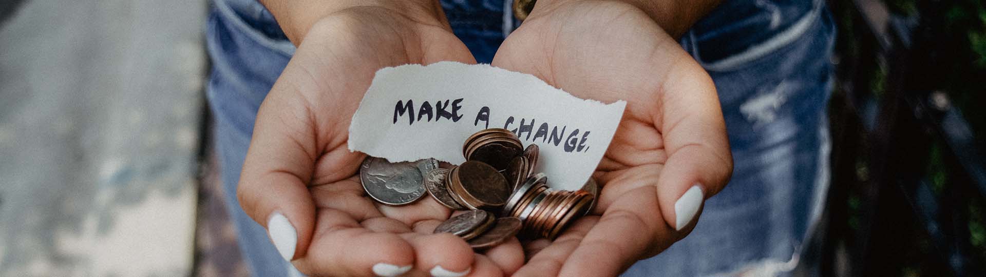 Hands holding out coins and a piece of paper reading, "MAKE A CHANGE."