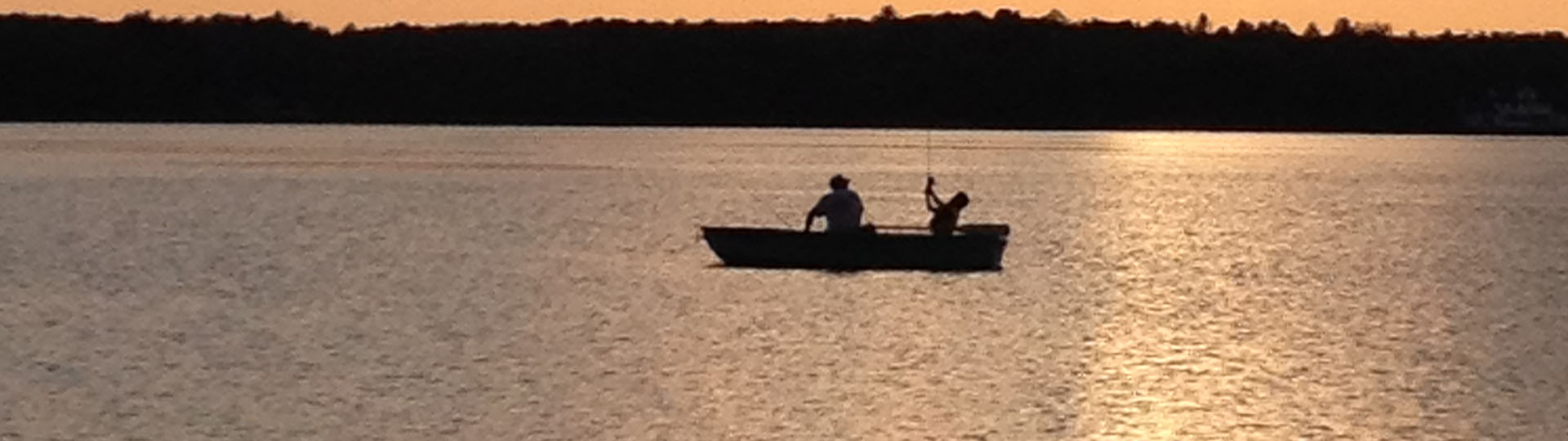 A man and his grandson boat fishing during sunrise
